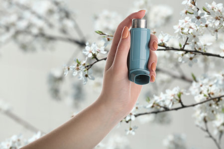 Young woman with inhaler outdoors on spring day, closeupの写真素材