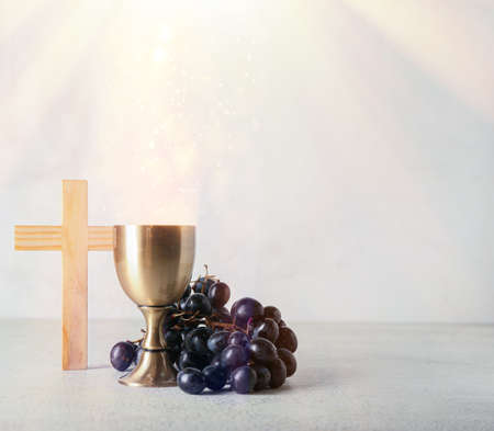 Chalice of wine with grapes and cross on light background. Christianity concept