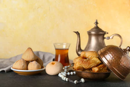 Tasty Eastern sweets and tea with tasbih on tableの写真素材