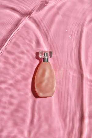 Bottle of perfume in water on color background, top viewの写真素材