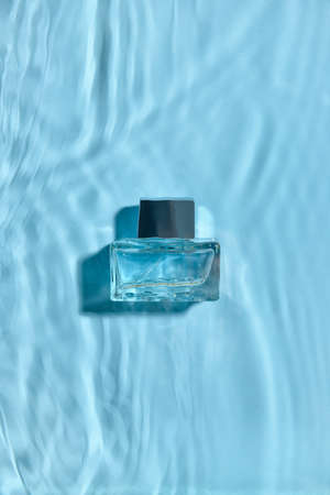 Bottle of perfume in water on color background, top viewの写真素材
