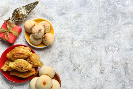 Tasty Eastern sweets with gift and Aladdin lamp on grunge background
