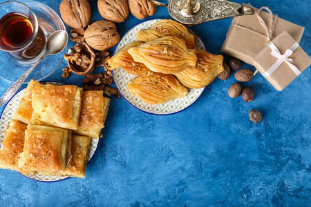 Tasty Turkish baklava with gifts and tea on color backgroundの写真素材