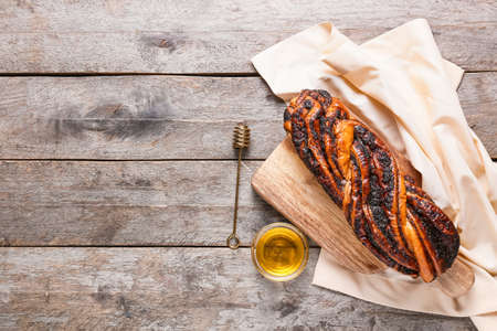 Board with tasty poppy seed bun and honey on wooden backgroundの写真素材