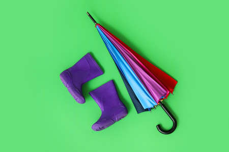 Stylish umbrella with gumboots on color backgroundの写真素材