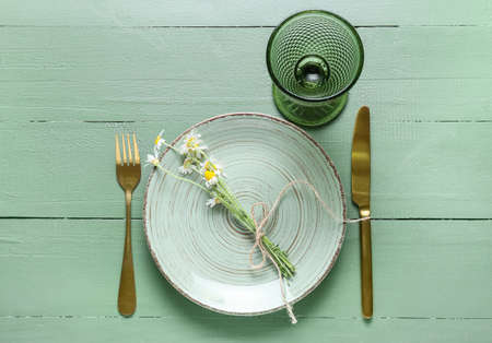 Beautiful table setting with chamomile flowers on color wooden backgroundの写真素材