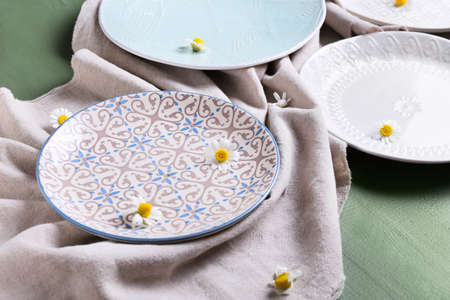 Beautiful plates with chamomile flowers on color wooden background
