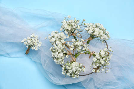 Composition with beautiful gypsophila boutonnieres and bridal veil on color background