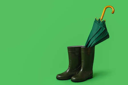 Stylish umbrella with gumboots on color backgroundの写真素材