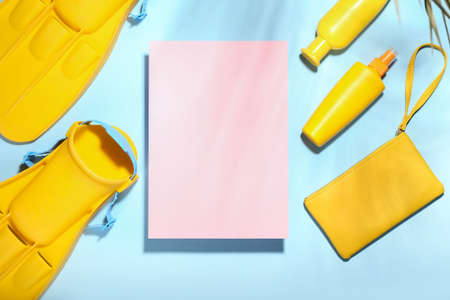 Set of beach accessories and blank sheet of paper on color background