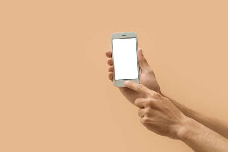 Male hands with modern mobile phone on color backgroundの写真素材