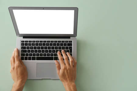 Male hands with modern laptop on color backgroundの写真素材