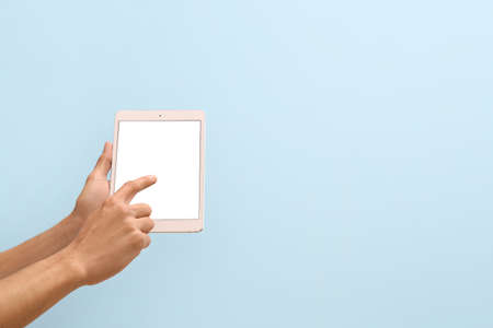 Male hands with modern tablet computer on color backgroundの写真素材