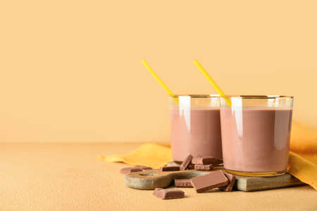Glasses of delicious chocolate milk on color backgroundの写真素材