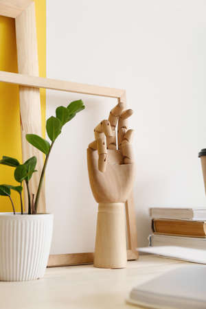 Wooden hand, books and houseplant on tableの写真素材
