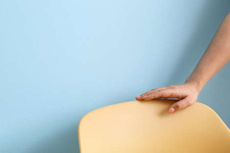 Female hand with yellow chair on blue background