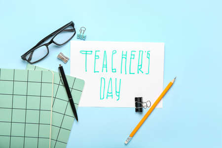 Paper with text TEACHER'S DAY, eyeglasses and stationery on color backgroundの写真素材