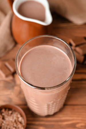 Glass of delicious chocolate milk on wooden background, closeup
