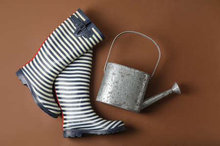 Watering can and gumboots on color backgroundの写真素材