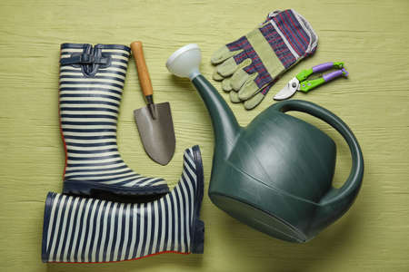 Watering can, gumboots and gardening tools on color wooden backgroundの写真素材