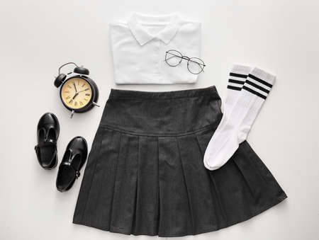 Stylish school uniform, eyeglasses and alarm clock on white backgroundの写真素材