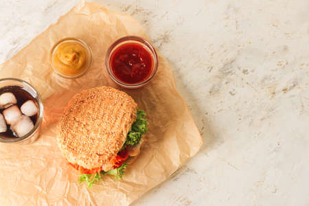 Fresh doner kebab in bun with sauces and glass of cola drink on light backgroundの写真素材