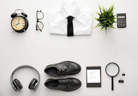 Composition with stylish school uniform, alarm clock, headphones and paper sheet with text BACK TO SCHOOL on white backgroundの写真素材