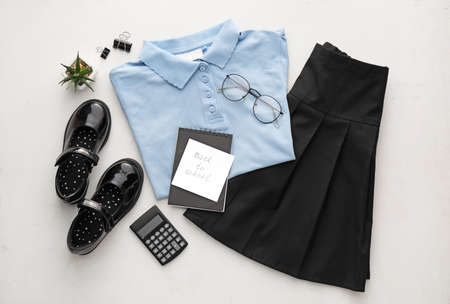 Stylish school uniform, stationery, eyeglasses and paper sheet with text BACK TO SCHOOL on light backgroundの写真素材