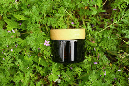 Jar of cosmetic product on grass background