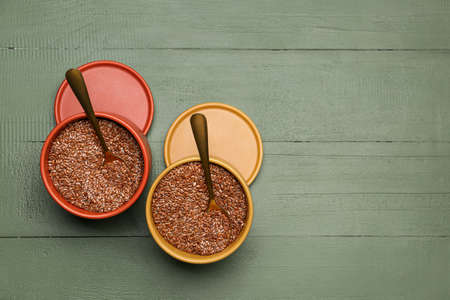 Boxes with flax seeds on color wooden background
