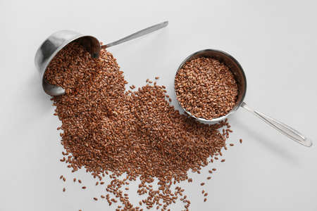 Ladles with flax seeds on light background