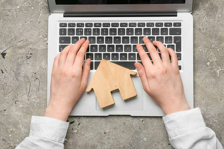 Real estate agent with wooden house using laptop on grunge backgroundの写真素材