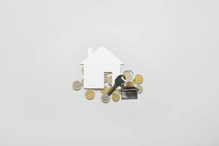 Paper house with key and coins on light backgroundの写真素材