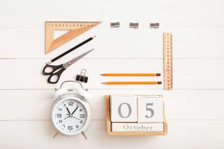 Cube calendar, alarm clock and stationery on white wooden backgroundの写真素材