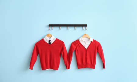 Modern school uniform hanging on color wallの写真素材