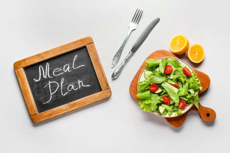 Chalkboard with words MEAL PLAN and fresh salad on white backgroundの写真素材