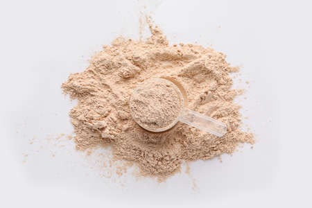 Measuring scoop with protein powder on white background