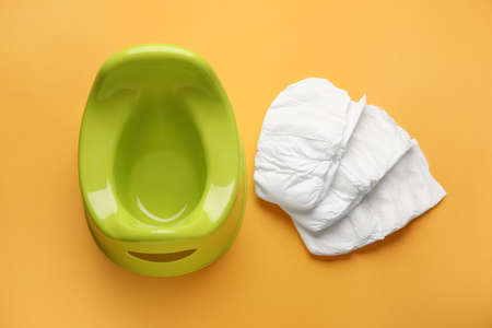 Potty and diapers on orange background