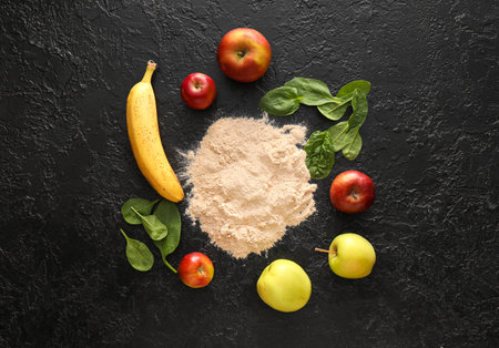 Frame made of apples, banana, spinach leaves and protein powder on dark backgroundの写真素材