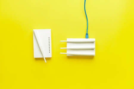 WiFi routers with antennas and network cable on color background