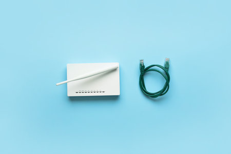 Wi-Fi router with antenna and network cable on color background