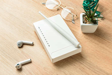 Wi-Fi router, earphones and eyeglasses on wooden background
