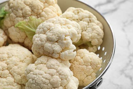 Colander with cauliflower cabbage on light background, closeup
