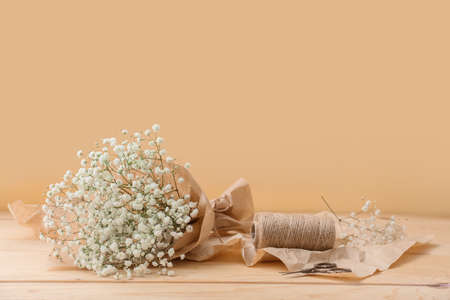 Bouquet of beautiful gypsophila flowers on wooden table near color wall