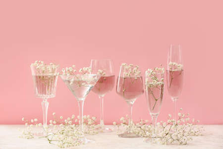 Glasses with beautiful gypsophila flowers on table near color wallの写真素材