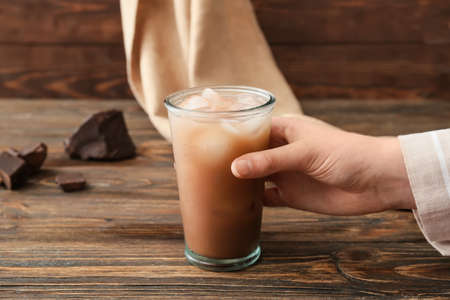 Woman with glass of tasty chocolate milk on wooden backgroundの写真素材