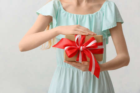 woman with gift on light background