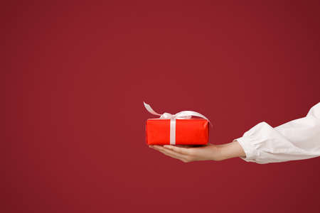 Female hand with gift on color backgroundの写真素材