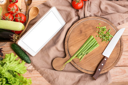 Tablet computer and fresh vegetables on the table in the kitchenの写真素材