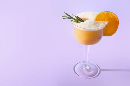 Glass of tasty whiskey sour cocktail on color backgroundの写真素材